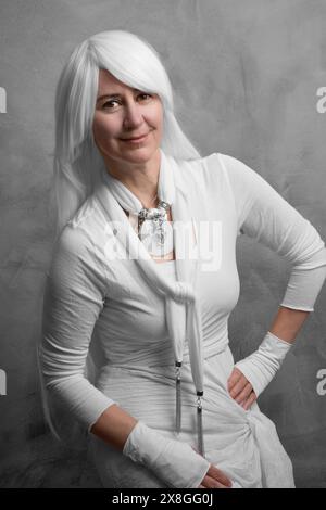 Portrait d'une femme de 50 ans aux longs cheveux blancs dans un style moderne et original sur fond gris Banque D'Images