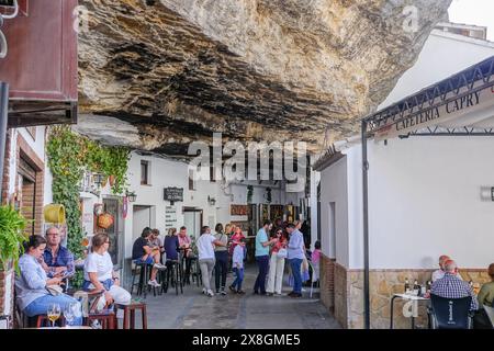 Les restaurants et les cafés se rassemblent le long de la Calle Cuevas de la Sombra sous la corniche rocheuse surplombant l'unique pueblos blanco de Setenil de las Bodegas, Espagne. Les habitants du petit village de Setenil vivent dans des maisons de grottes depuis l'époque néolithique. Banque D'Images