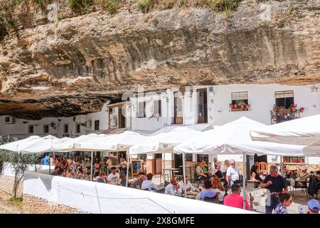 Les restaurants et les cafés se rassemblent sous un surplomb rocheux le long de la Terrazas Calle Cuevas del sol dans l'unique pueblos blanco de Setenil de las Bodegas, Espagne. Les habitants du petit village de Setenil vivent dans des maisons de grottes depuis l'époque néolithique. Banque D'Images