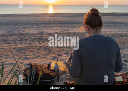 Paisible jeune femme artiste tenant palette peignant un tableau sur un chevalet à la plage. Banque D'Images