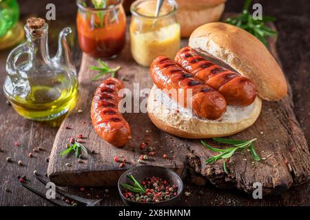 Petit pain chaud avec saucisse rôtie faite sur le gril de feu de joie. Saucisse grillée aux épices. Banque D'Images