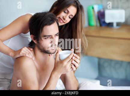 Homme, femme et embrasser avec le café au lit avec soin, se lier et se réveiller avec salut à la maison. Couple, chambre et toucher avec connexion, amour et Banque D'Images