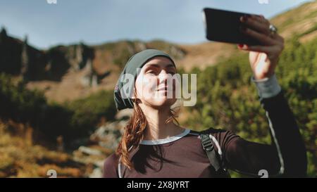 Jeune femme capturant le selfie paysage de scène de montagne dynamique avec téléphone portable. Touriste actif prendre une photo. Caucasian Girl randonneur aime moment. Voyage, tourisme, trekking, randonnée, mode de vie actif Banque D'Images