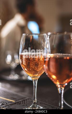 Gros plan de deux verres de vin mousseux rose avec une personne floue en arrière-plan Banque D'Images