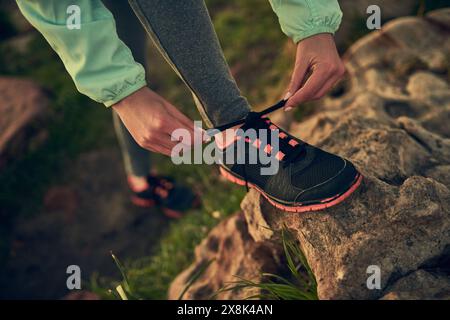 Personne, mains et chaussure de nouage avec rocher de randonneur pour la promenade du matin ou trekking sur la montagne en plein air. Gros plan sur la préparation, la préparation ou la cravate humaine Banque D'Images