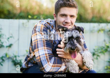 Heureux, homme et portrait se liant avec le chien dans le jardin, jouant et montrant de l'affection pour son chiot à la maison. Joyeux, aimant et masculin appréciant le temps avec Banque D'Images