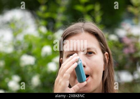 La jeune femme souffre du rhume des foins et inhale l'asthme spray à l'extérieur, Fribourg, Bade-Wuerttemberg, Allemagne Banque D'Images