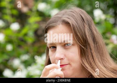 La jeune femme souffre du rhume des foins et utilise un mouchoir en papier à l'extérieur, Fribourg, Bade-Wuerttemberg, Allemagne Banque D'Images