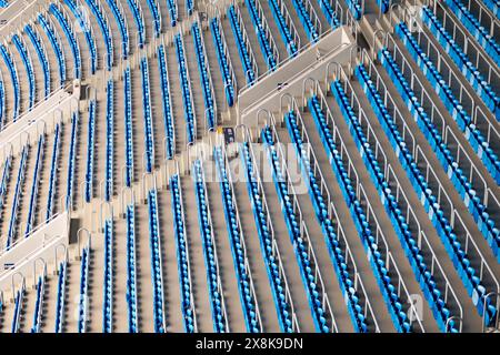 Vue grand angle de nombreuses rangées de sièges bleus vides du stade. Les sièges sont disposés uniformément, créant un motif symétrique et organisé. Banque D'Images