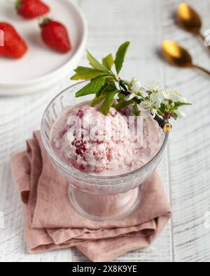 Crème glacée aux fraises maison servie dans un bol en verre, garnie de tranches de fraises fraîches Banque D'Images