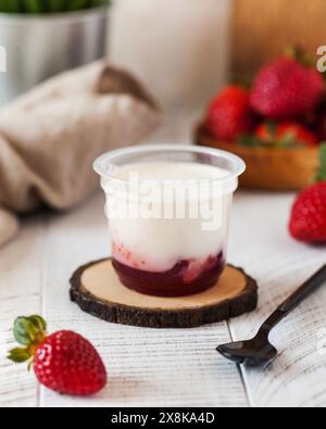 Yaourt avec remplissage de fraise dans une tasse en plastique. Panna cotta avec confiture de baies Banque D'Images