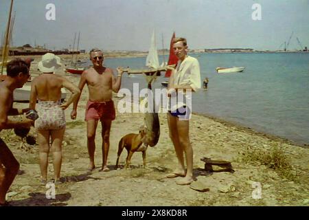 Deux hommes européens avec un gros poisson fraîchement pêché en mer à Accra, Ghana vers 1958 Banque D'Images