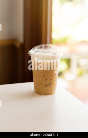 Un cappuccino glacé en plastique invitant, recouvert de mousse de lait et de glace, prêt pour une gorgée rafraîchissante. Banque D'Images