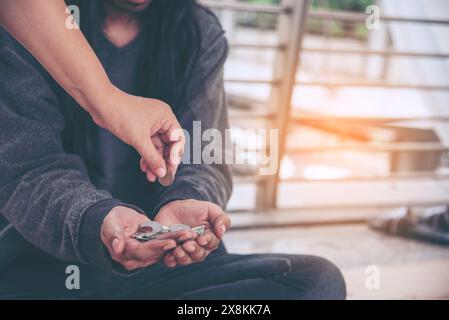 Femme aidant les mains aux sans-abri pauvreté mendiant homme tenant la main demandant l'argent travail et espérant de l'aide dans la ville sale impuissante assis dans les rues Banque D'Images