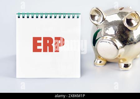 Word ERP (abréviation de Enterprise Resource Planning) écrit sur un cahier avec une tirelire à côté Banque D'Images