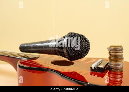 Microphone sur cordes ukulélé, et une pile de pièces, concept de revenu de musique, soft focus Banque D'Images