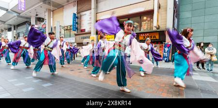 Danseurs yosakoi jouant dans une galerie marchande à Kumamoto, au Japon. Troupe de jeunes femmes vêtues de danse yukata à manches longues. Flou de mouvement. Banque D'Images