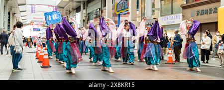 Danseurs yosakoi jouant dans une galerie marchande à Kumamoto, au Japon. Troupe de jeunes femmes vêtues de yukata à manches longues dansant pendant que les acheteurs regardent. Banque D'Images