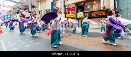 Danseurs yosakoi jouant dans une galerie marchande à Kumamoto, au Japon. Troupe de jeunes femmes vêtues de yukata à manches longues dansant avec les bras tourbillonnant. Banque D'Images