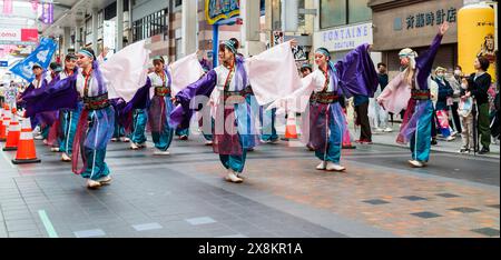 Danseurs yosakoi jouant dans une galerie marchande à Kumamoto, au Japon. Troupe de jeunes femmes vêtues de yukata à manches longues dansant pendant que les acheteurs regardent. Banque D'Images