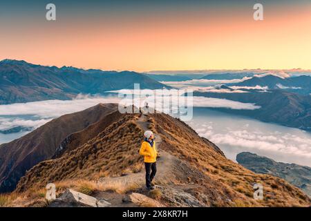 Réalisation femme de randonnée asiatique debout sur le point de vue de Roys Peak avec le lever du soleil et le brouillard sur Wanaka en automne à la Nouvelle-Zélande Banque D'Images