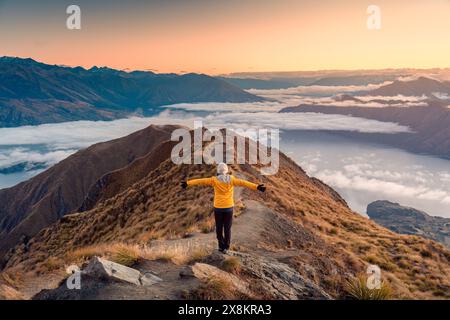 Réalisation femme de randonnée asiatique debout sur le point de vue de Roys Peak avec le lever du soleil et le brouillard sur Wanaka en automne à la Nouvelle-Zélande Banque D'Images