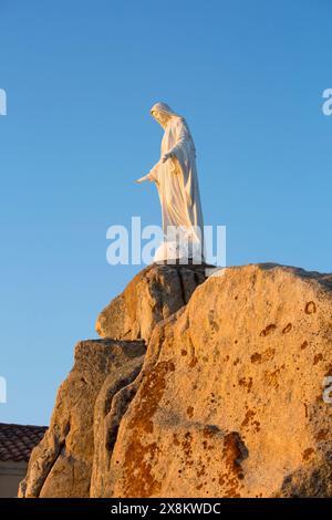 Calvi, haute-Corse, Corse, France. Imposante statue de la Vierge Marie sur un éperon rocheux à la Chapelle notre Dame de la Serra, au lever du soleil. Banque D'Images