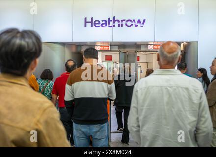 Les gens attendent pour saluer leurs amis et parents devant un panneau indiquant « Heathrow » à l'aéroport d'Heathrow, terminal 4, Londres, Royaume-Uni. Banque D'Images