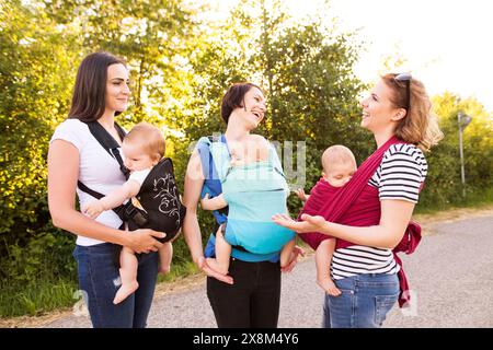 Mères portant des bébés dans des porte-bébés, des écharpes ou des enveloppes. Babywear. Banque D'Images