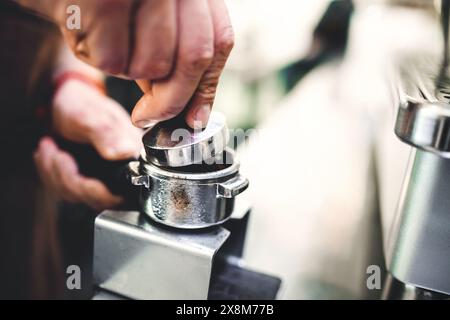 Gros plan sur les mains du barista travaillant dans un café. Barman dans un tablier préparant une boisson au café. Banque D'Images