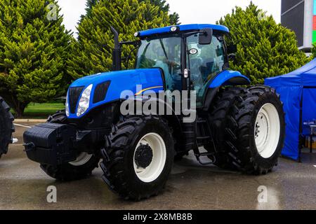 Les nouveaux tracteurs agricoles bleus de différents modèles se tiennent dans une rangée sur le site d'exposition en préparation pour le début des semis de printemps de l'agriculture Banque D'Images