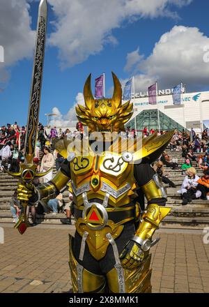 Londres, Royaume-Uni. 26 mai 2024. Un cosplayer en tenue de « Iron Warrior » pose dans son lourd costume doré. Un participant pose dans une tenue comme Stolas de 'helluva Boss'. MCM Comic Con à Excel London est occupé le dernier jour. Cosplayers, fans d'anime, de bandes dessinées, de jeux et de films se réunissent pour ce grand événement de trois jours du 24-26 au 30 mai. Crédit : Imageplotter/Alamy Live News Banque D'Images