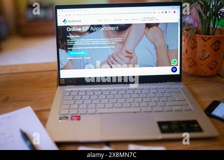 Écran d'ordinateur portable sur une table de salon montrant une page de réservation de rendez-vous GP en ligne pour Dr En ligne avec ordinateur portable et stylo. Banque D'Images