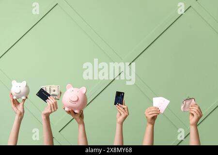Mains féminines avec cartes de crédit, argent, portefeuille et tirelires sur fond vert Banque D'Images