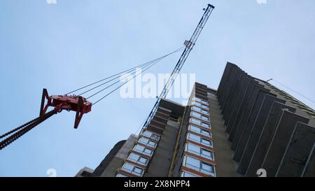 Travaux de grue haute sur le chantier. Agrafe. Construction des bâtiments résidentiels, complexe résidentiel de grande hauteur en construction. Banque D'Images