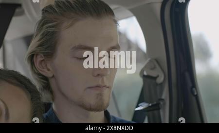 Jeune couple dort pendant le voyage en voiture. Stock. Femme dort sur l'épaule du jeune homme en voiture. Jeune couple attrayant s'endort pendant le trajet en voiture Banque D'Images