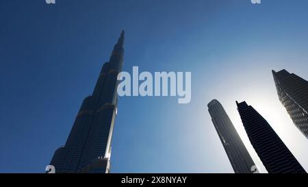 Vue en bas angle de Burj Khalifa avec le ciel bleu derrière. Action. Gratte-ciel de façade en verre moderne dans le centre-ville. Banque D'Images