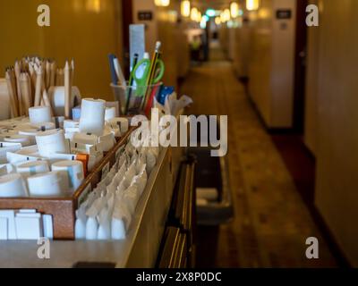 Chariot de fournitures d'entretien ménager de l'hôtel avec des articles de toilette jetables pour les clients avec emballage blanc et papeterie sur le couloir de la chambre d'hôtel et la passerelle b Banque D'Images