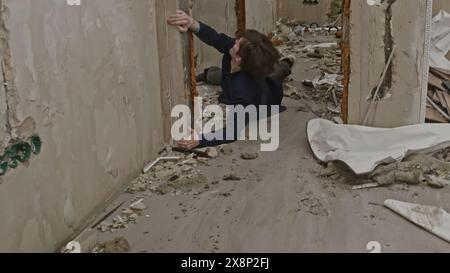 Homme essayant de survivre dans un bâtiment explosé en ruine. Pince de stock. Concept de vie dans le monde post-apocalyptique. Banque D'Images