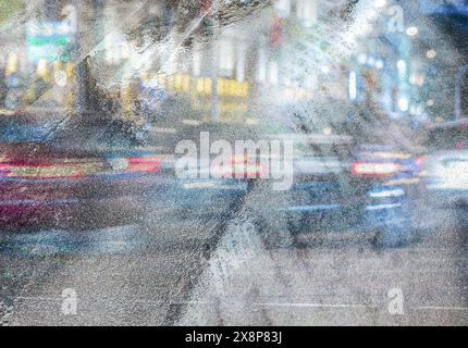 route asphaltée humide avec circulation urbaine et sentiers de feux de voiture. image urbaine multi-exposée à la nuit pluvieuse. Banque D'Images