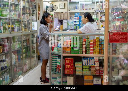 SAIGON, VIETNAM, 17 décembre 2017, Une jeune femme consulte l'achat de médicaments avec un pharmacien dans une pharmacie du soir Banque D'Images