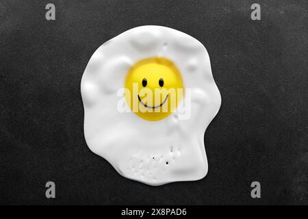 Oeuf frit sur une poêle avec un visage d'émoticône souriant. Illustration alimentaire créative. Rendu 3D. Banque D'Images