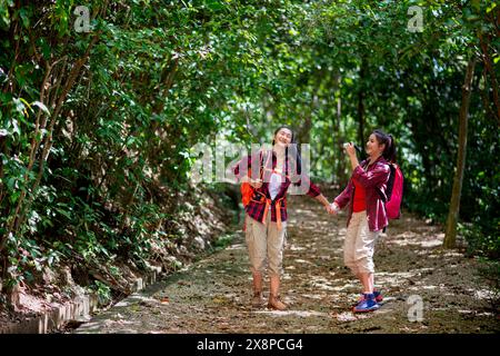 Deux randonneuses asiatiques marchent dans la forêt. Les randonneuses féminines regardent autour et ont pris des photos en marchant dans la forêt avec bonheur et joie pendant leur vie Banque D'Images