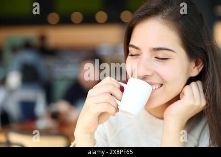 Femme heureuse buvant et souriant dans un café Banque D'Images