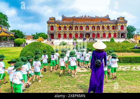 Un groupe d'élèves vietnamiens du primaire ont reçu l'instruction de leur professeur de famille de visiter la citadelle interdite à Hue, au Vietnam Banque D'Images