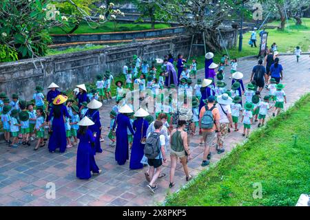 Un groupe d'élèves vietnamiens du primaire ont reçu l'instruction de leur professeur de famille de visiter la citadelle interdite à Hue, au Vietnam Banque D'Images