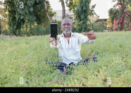 Élevage de pois chiches indiens, fermier indien heureux tenant le téléphone portable dans les mains, pauvre fermier heureux Banque D'Images