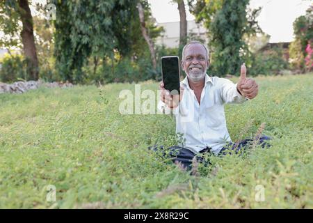 Élevage de pois chiches indiens, fermier indien heureux tenant le téléphone portable dans les mains, pauvre fermier heureux Banque D'Images