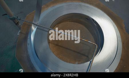 Déroulement d'une ligne métallique sur une machine. Créatif. Bobine de ligne métallique plate sur machine industrielle. Ligne de plaques tournantes dans la production métallurgique Banque D'Images