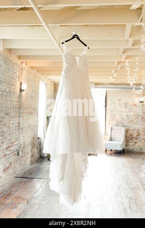 Élégante robe de mariée blanche suspendue dans une pièce rustique de style industriel Banque D'Images